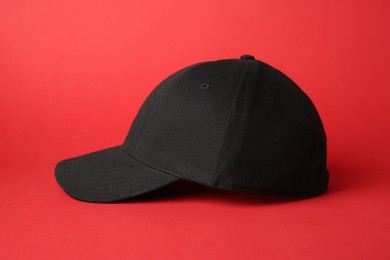 Photo of Stylish black baseball cap on red background