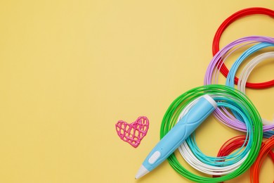 Photo of Stylish 3D pen, colorful plastic filaments and heart figure on yellow background, flat lay. Space for text