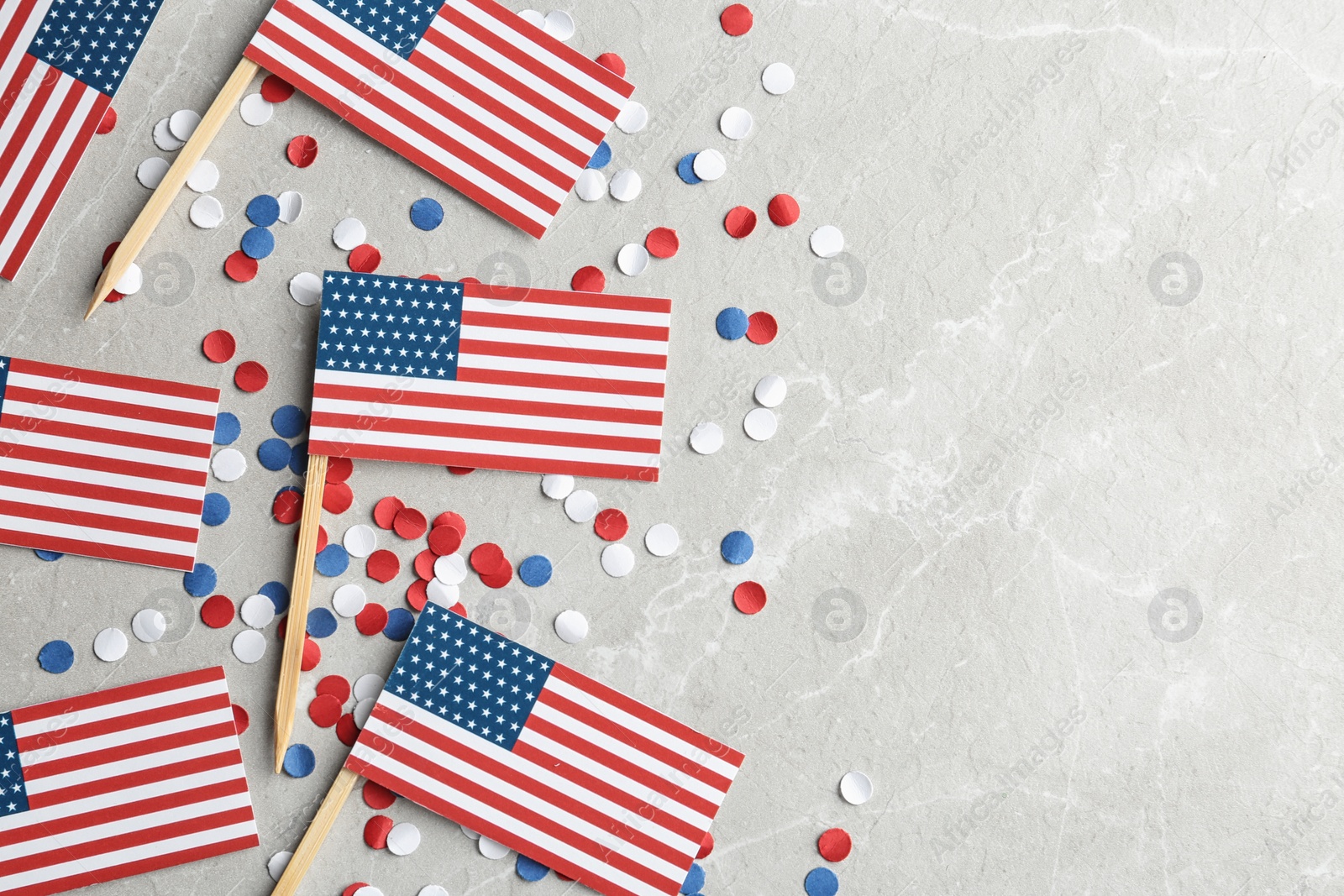 Photo of Flat lay composition with USA flags on light background, space for text. Happy Independence Day