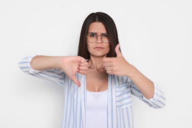 Photo of Young woman showing thumbs up and down on white background
