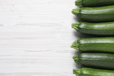 Photo of Raw ripe zucchinis on white wooden table, flat lay. Space for text