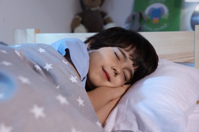 Cute little boy sleeping in bed at home