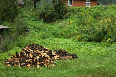 Pile of cut firewood on fresh green grass outdoors, space for text