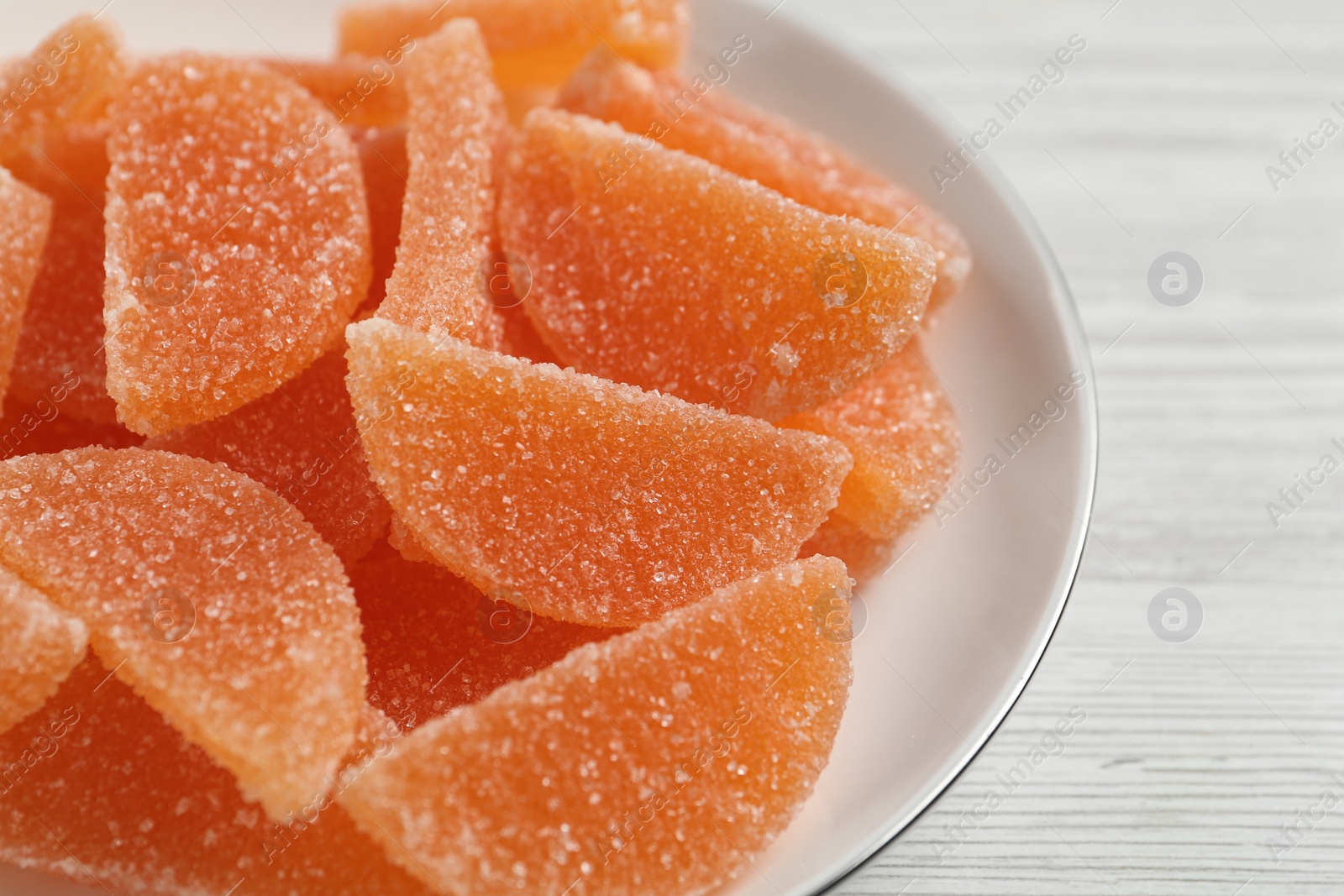 Photo of Tasty orange jelly candies on white table, closeup