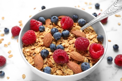 Tasty homemade granola with berries on white marble table, closeup. Healthy breakfast