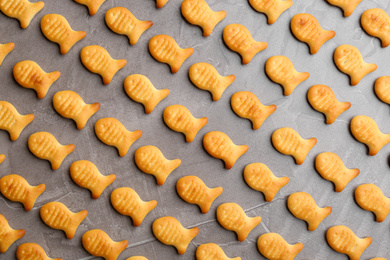 Photo of Delicious goldfish crackers on grey table, flat lay