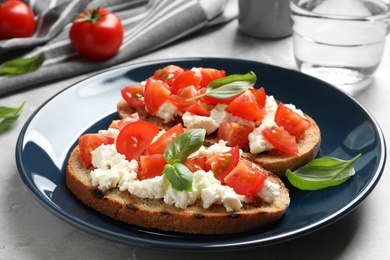 Plate with tasty bruschettas on grey table