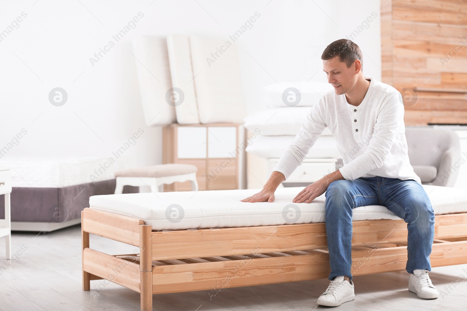 Photo of Man touching mattress in furniture store. Space for text