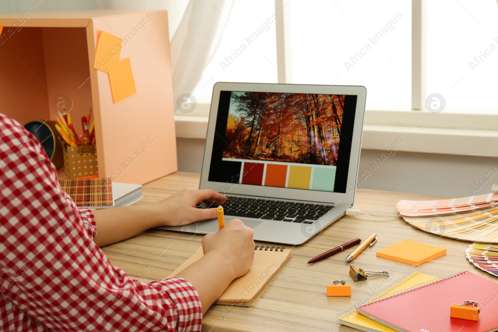 Photo of Female designer working at wooden table indoors, closeup