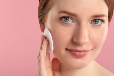 Photo of Beautiful woman with freckles wiping face on pink background, closeup. Space for text