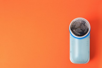 Photo of Fabric shaver on orange background, top view. Space for text