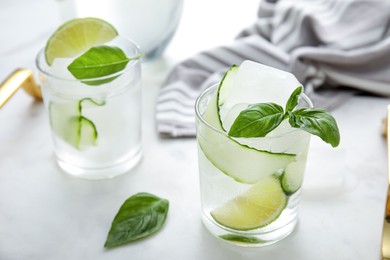 Photo of Tasty fresh cucumber water with sliced lime and basil on white table