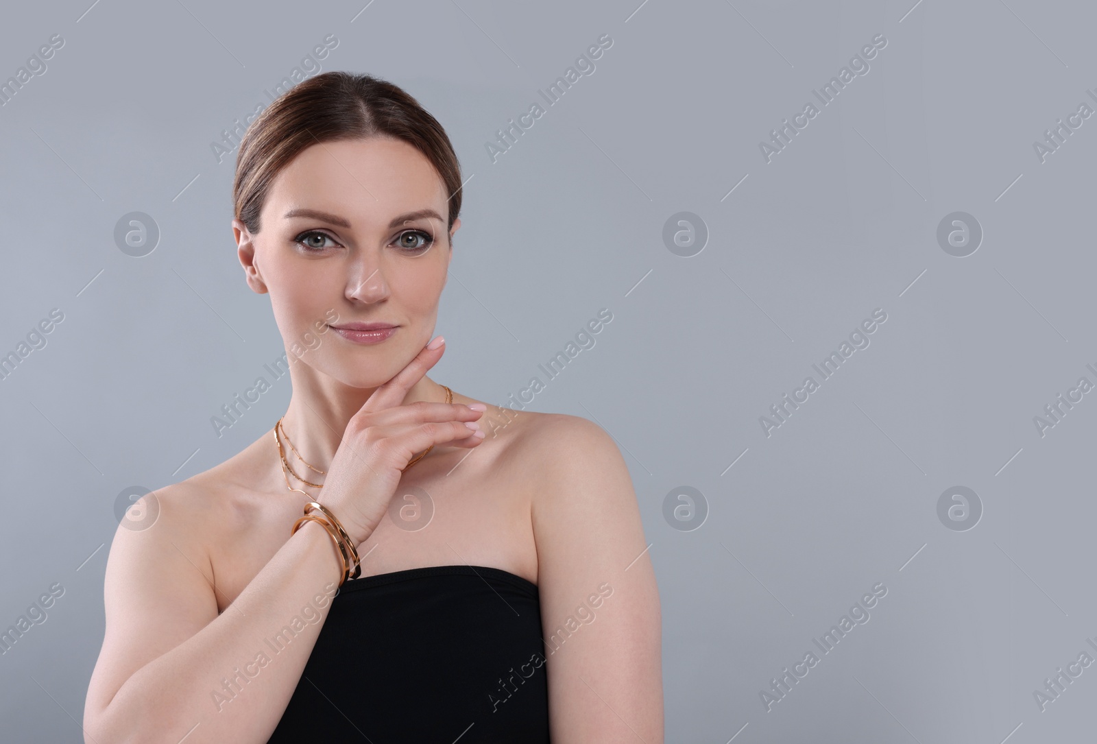 Photo of Beautiful woman with elegant jewelry on light grey background. Space for text