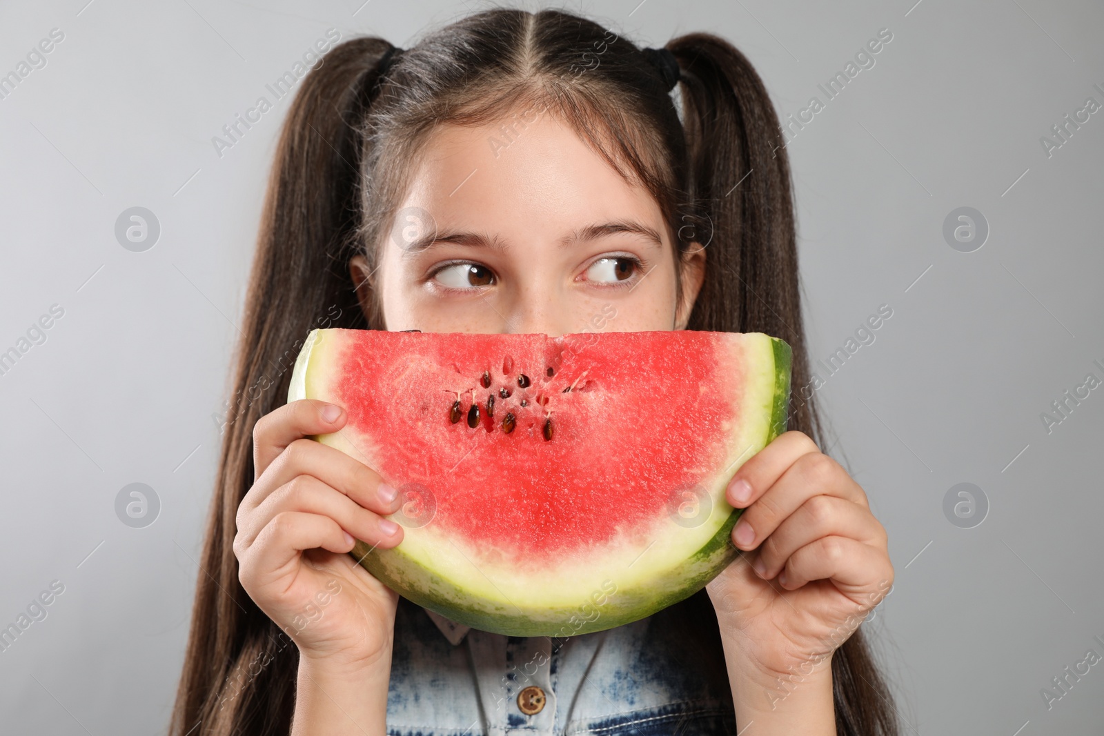 Photo of Cute little girl with watermelon on grey background