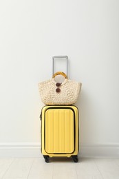 Photo of Suitcase packed for trip and summer accessories near white wall indoors