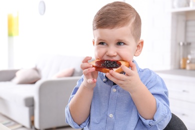 Photo of Cute little boy eating toast with sweet jam at home