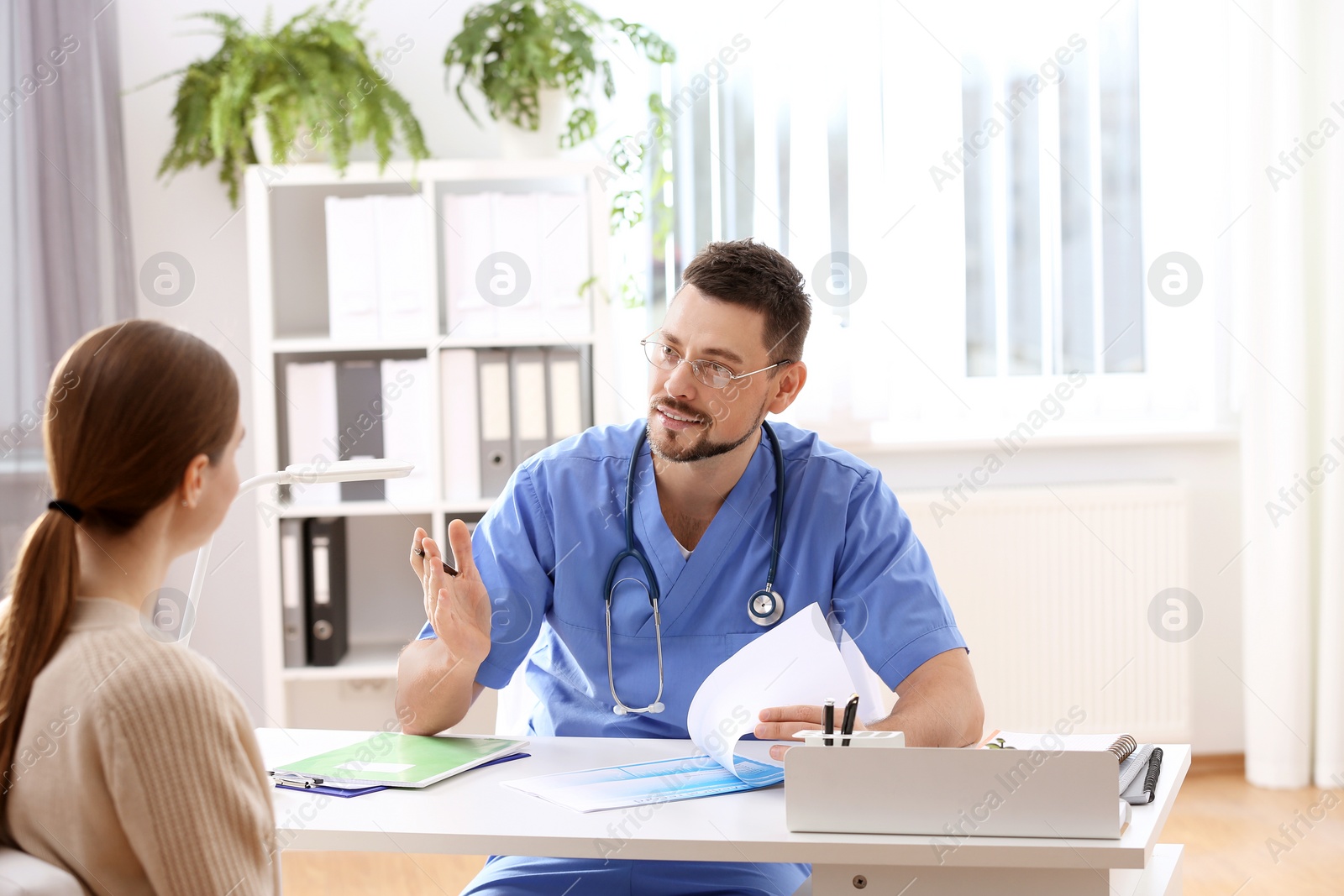 Photo of Doctor consulting patient at desk in clinic