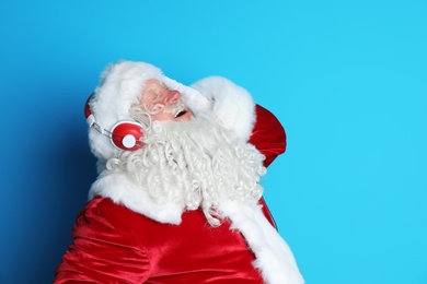 Photo of Authentic Santa Claus listening to music on color background