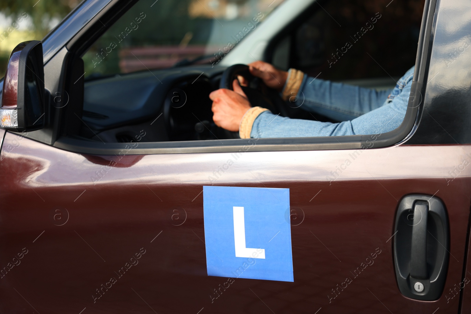 Photo of Learner driver driving car with L-plate, view from outside. Driving school