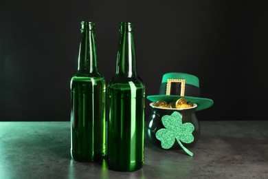 Photo of St. Patrick's day celebration. Beer in green bottles, leprechaun hat, pot of gold and decorative clover leaf on grey table