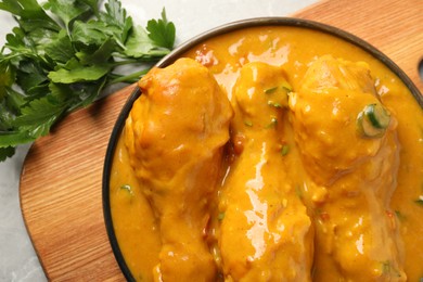 Tasty chicken curry and parsley on grey textured table, flat lay