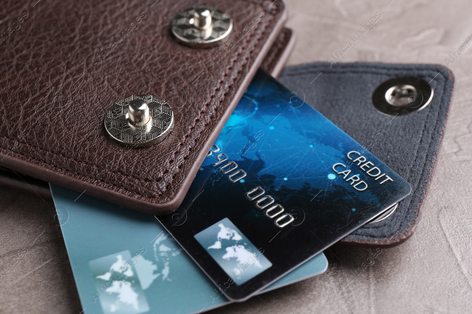 Photo of Leather wallet with credit cards on grey textured table, closeup