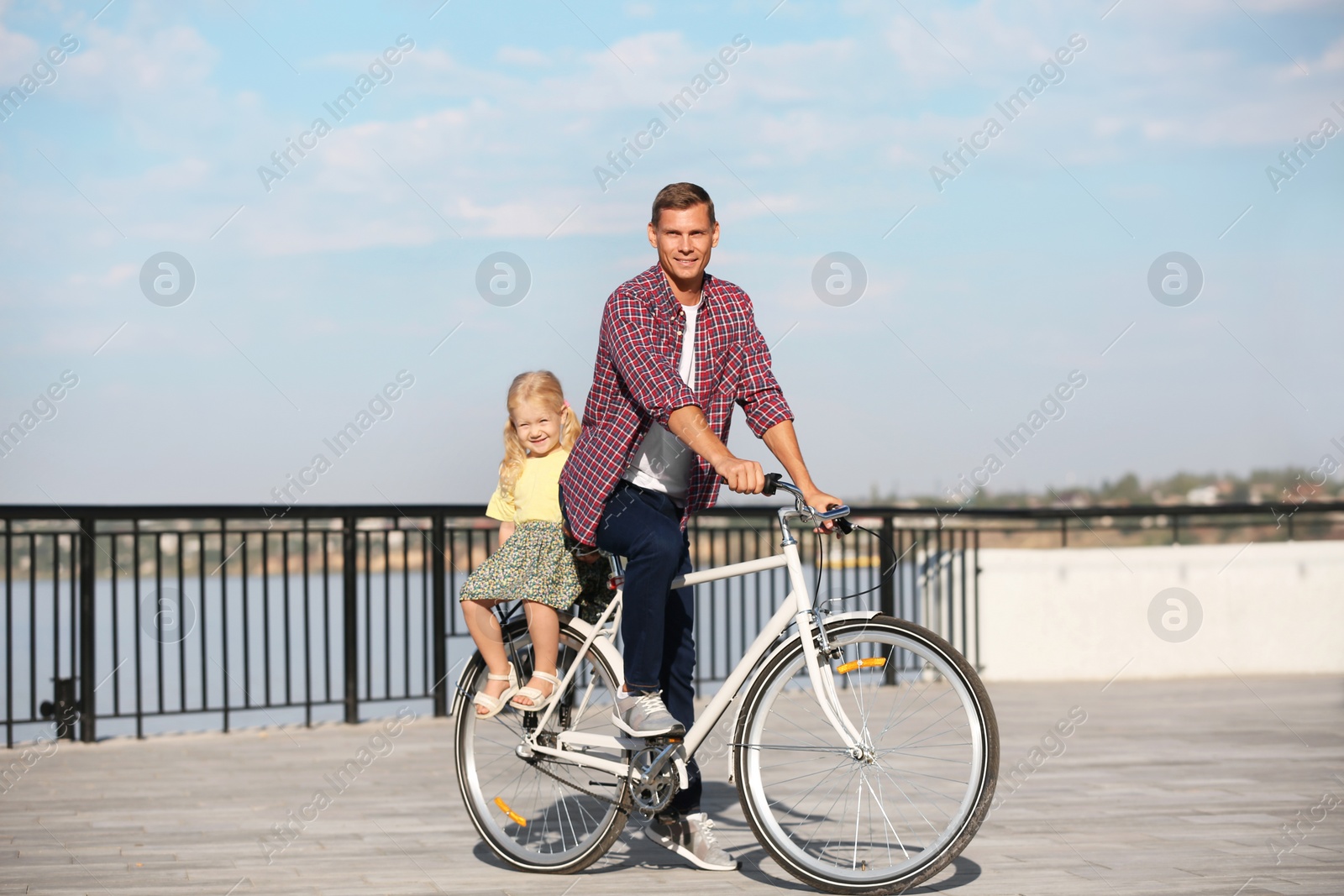 Photo of Father and daughter riding bicycle outdoors on sunny day