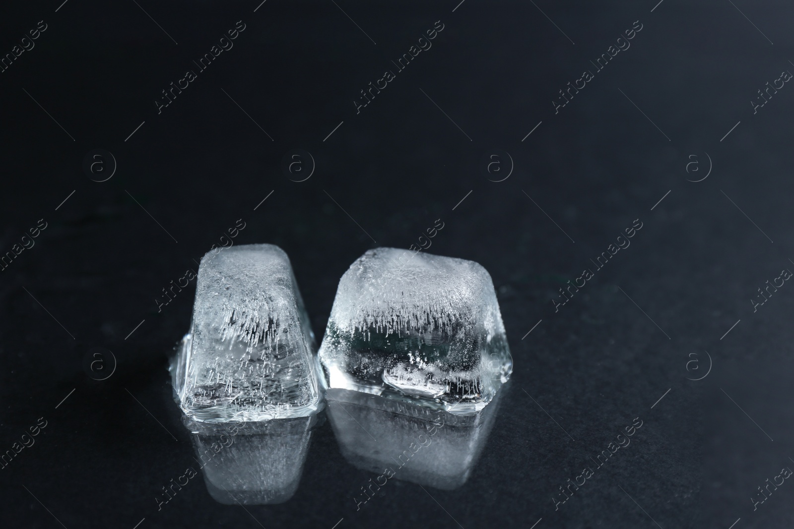 Photo of Ice cubes on wet black surface, closeup