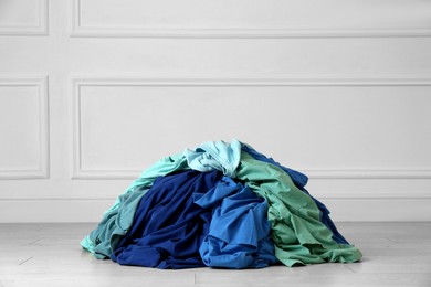 Photo of Pile of dirty clothes on floor near light wall indoors