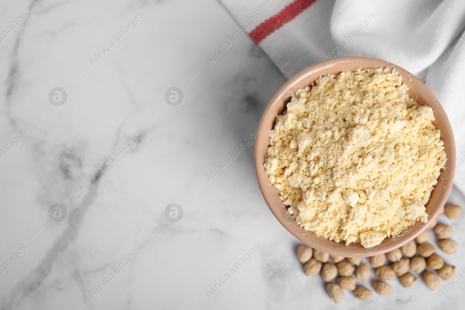 Photo of Chickpea flour in bowl and seeds on white marble table, top view. Space for text