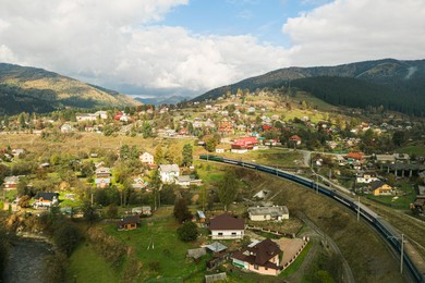 Image of Aerial view of train on bridge and mountain village