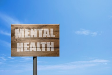 Image of Wooden sign with phrase Mental Health against blue sky on sunny day