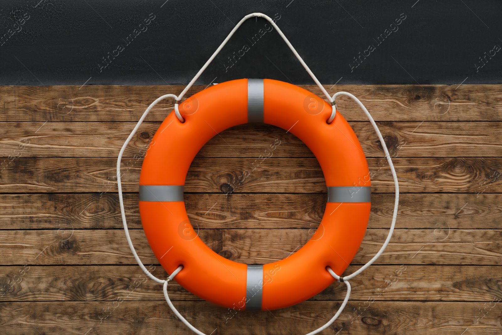 Photo of Orange lifebuoy hanging on wall. Rescue equipment