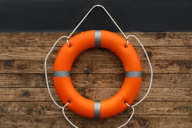 Photo of Orange lifebuoy hanging on wall. Rescue equipment