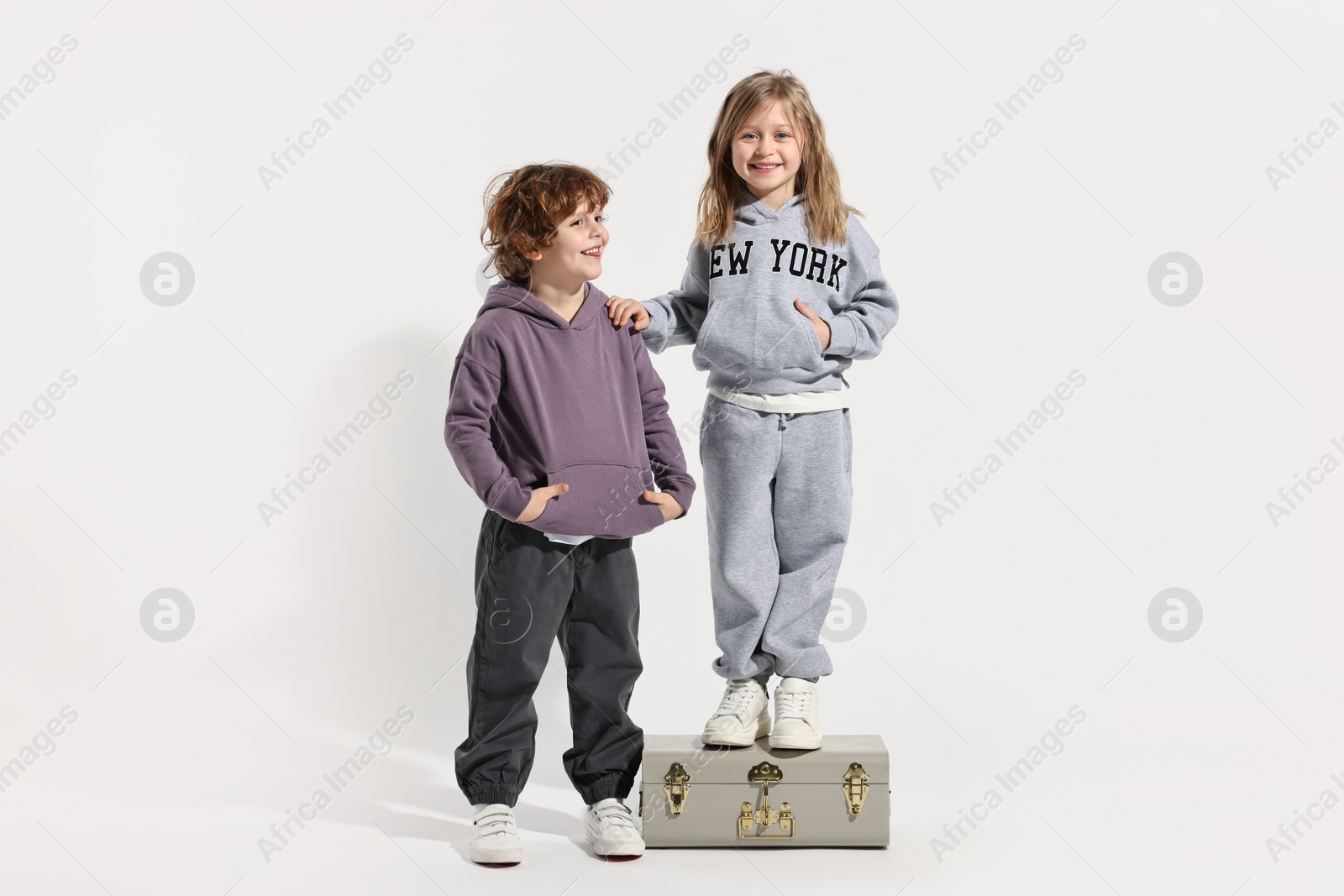 Photo of Fashion concept. Stylish children with vintage suitcase on white background