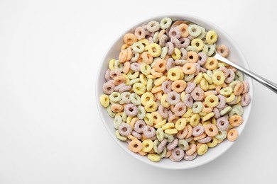 Tasty cereal rings in bowl and spoon on white table, top view. Space for text