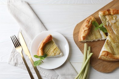 Photo of Freshly baked rhubarb pie, stalks and cutlery on white wooden table, flat lay