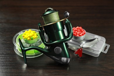 Photo of Fishing tackle. Spinning reel, baits and lure on dark wooden background, closeup