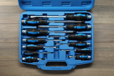 Photo of Set of screwdrivers in open toolbox on wooden table, top view