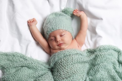 Photo of Cute little baby sleeping under knitted plaid in bed, top view