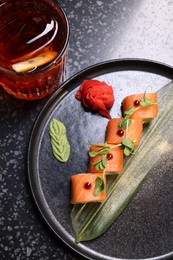 Photo of Delicious sushi rolls served with alcoholic Negroni cocktail on dark table, flat lay