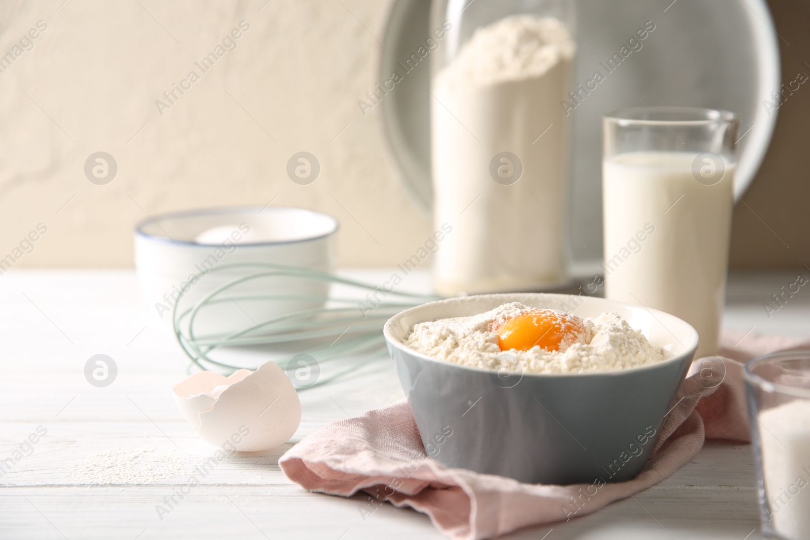 Photo of Making dough. Flour with yolk in bowl on white wooden table, closeup