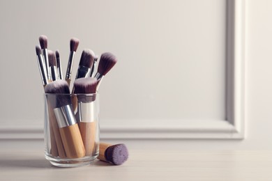Set of professional makeup brushes on table against white background, space for text