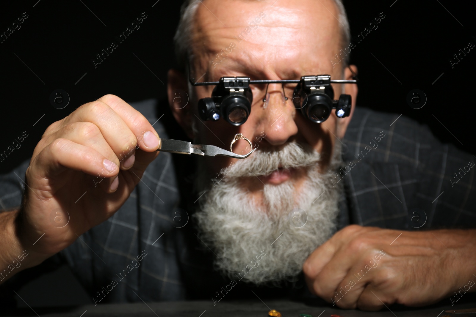 Photo of Male jeweler evaluating diamond ring in workshop