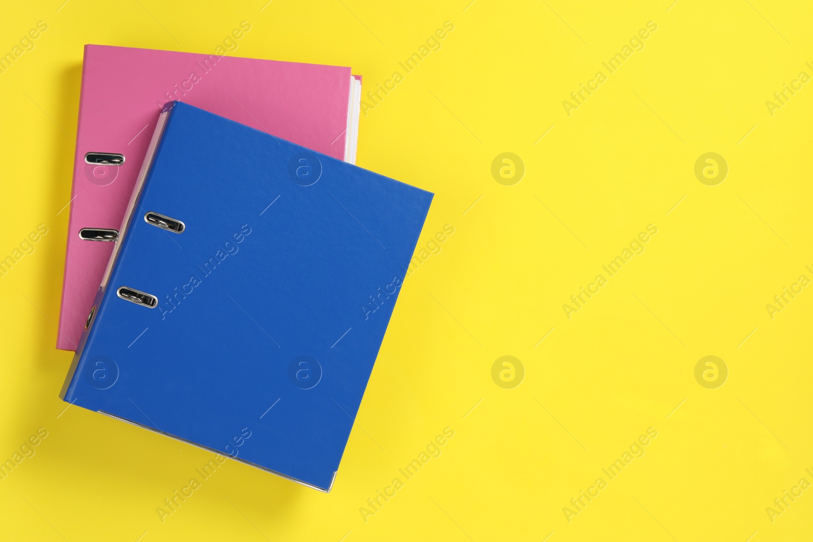 Photo of Office folders on yellow background, flat lay. Space for text