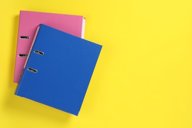 Office folders on yellow background, flat lay. Space for text