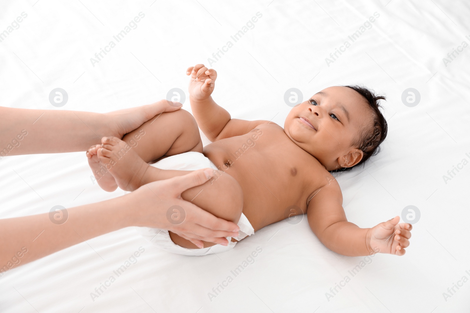 Photo of Mother and her cute child on white bed. Baby massage and exercises