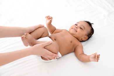 Photo of Mother and her cute child on white bed. Baby massage and exercises