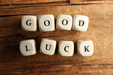 Photo of Cubes with phrase GOOD LUCK on wooden table, flat lay