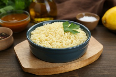 Photo of Tasty couscous with parsley on wooden table, closeup